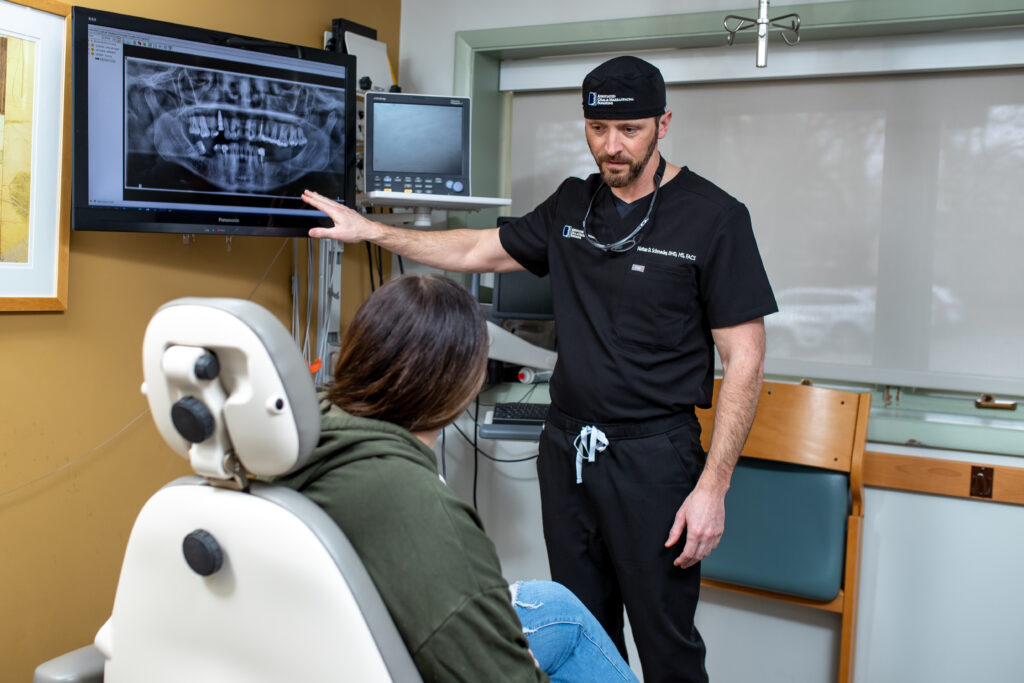 Dr Schroeder an oral surgeon at Associated Oral and Maxillofacial Surgeons looking at xrays with a patient