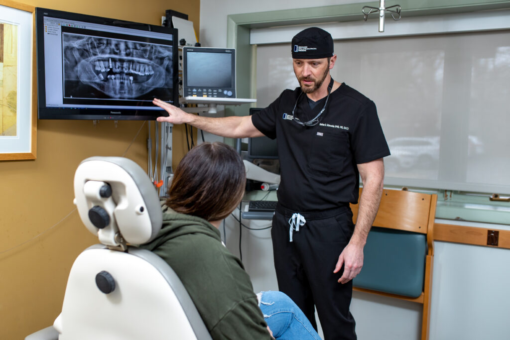 Dr Schroeder an oral surgeon at Associated Oral and Maxillofacial Surgeons looking at xrays with a patient