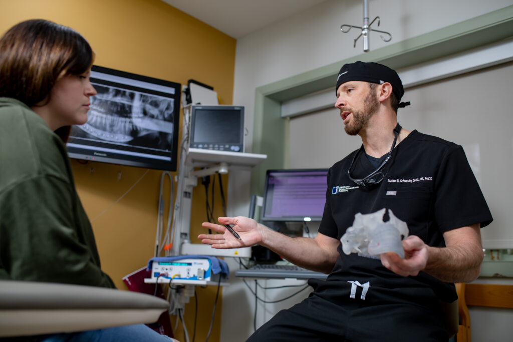 Dr Schroeder an oral surgeon at Associated Oral and Maxillofacial Surgeons speaking with a patient